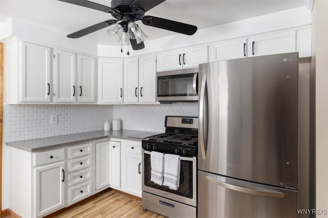 kitchen with white cabinets, a ceiling fan, decorative backsplash, stainless steel appliances, and light wood-type flooring