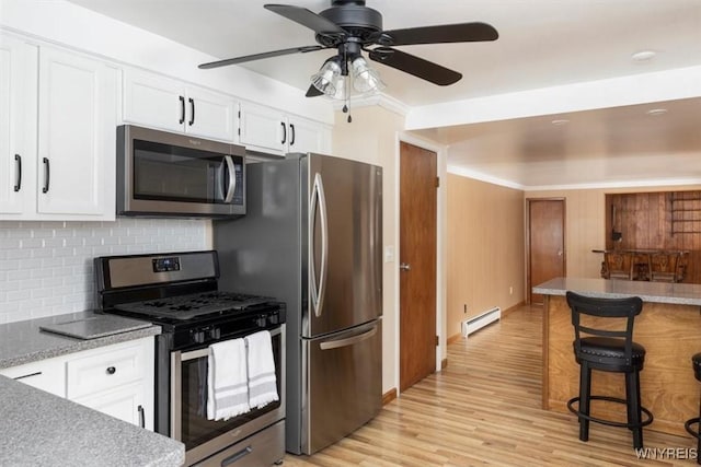 kitchen featuring appliances with stainless steel finishes, baseboard heating, white cabinetry, and light wood-style floors