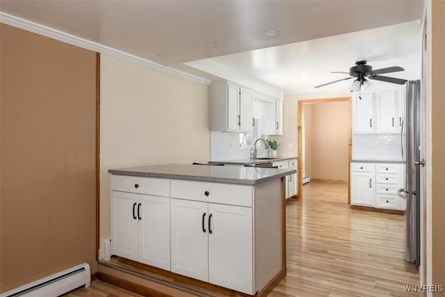 kitchen featuring a baseboard heating unit, a sink, light wood-style floors, white cabinets, and crown molding