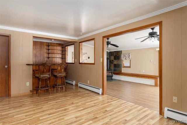 interior space featuring light wood-style floors, a baseboard radiator, and a wood stove