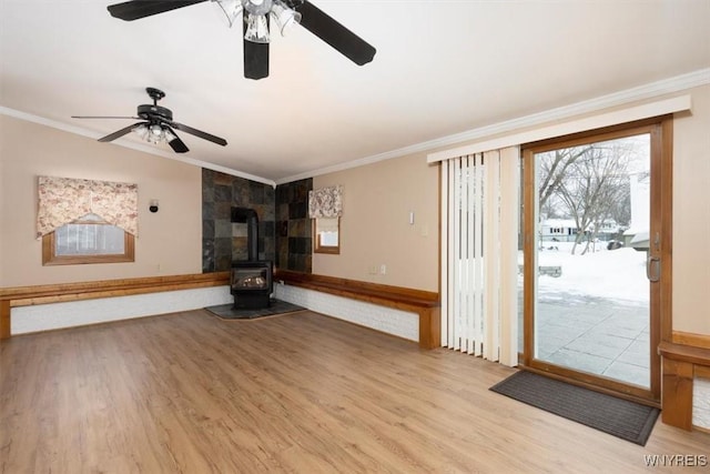 unfurnished living room with ornamental molding, lofted ceiling, a wood stove, and light wood-style flooring