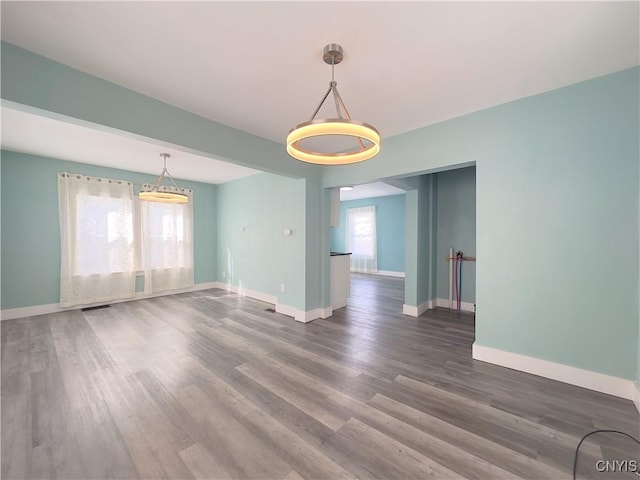 unfurnished room featuring dark wood-type flooring, visible vents, and baseboards