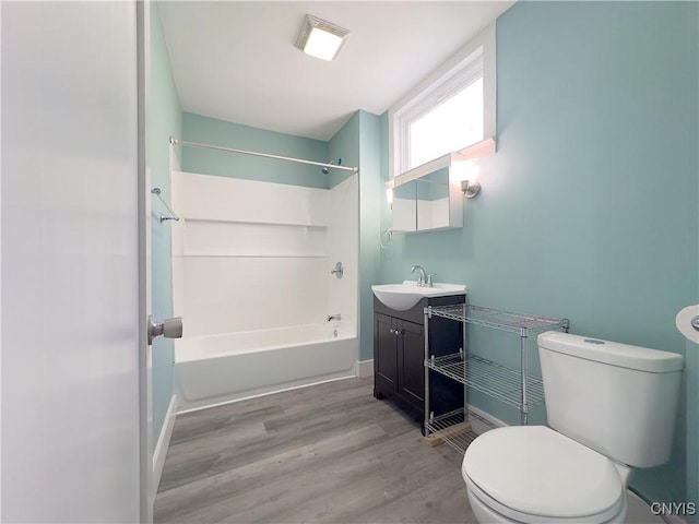 full bath featuring toilet, vanity, shower / tub combination, wood finished floors, and baseboards