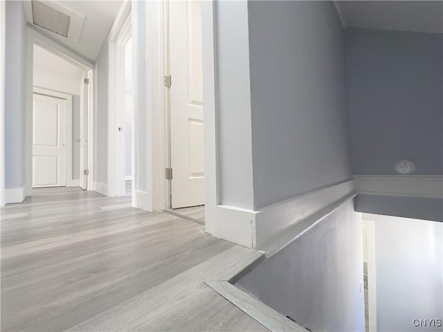 hall featuring light wood-style flooring, visible vents, and attic access