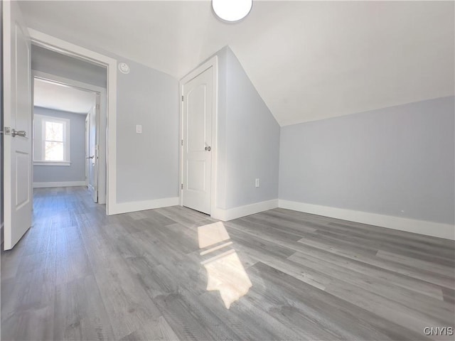 bonus room with lofted ceiling, light wood-style floors, and baseboards