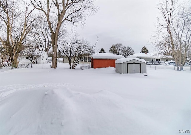 yard covered in snow featuring a storage unit and an outbuilding