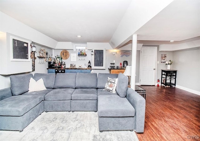 living area with baseboards, indoor wet bar, and wood finished floors