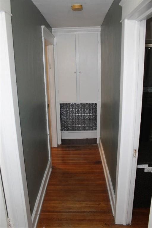 hallway with dark wood-type flooring and baseboards