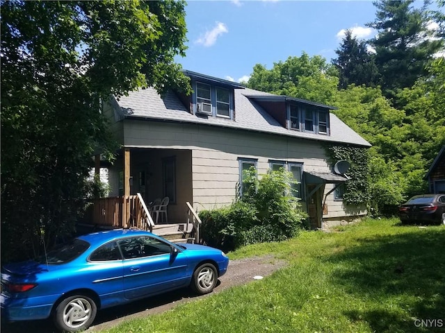 exterior space with a front yard, roof with shingles, and cooling unit