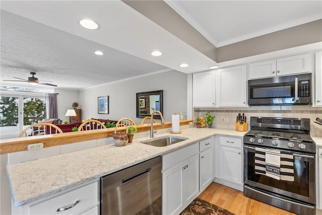 kitchen featuring stainless steel appliances, white cabinetry, a sink, and a peninsula