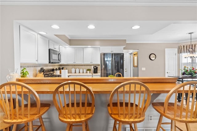 kitchen featuring white cabinetry, appliances with stainless steel finishes, decorative backsplash, and crown molding