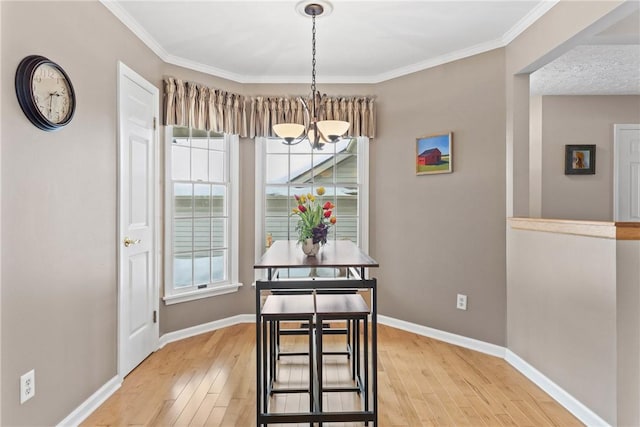 dining space with ornamental molding, a notable chandelier, baseboards, and wood finished floors