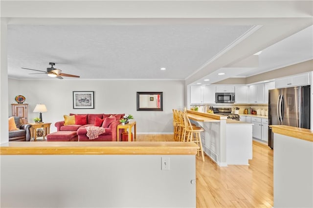 living room featuring recessed lighting, crown molding, light wood-style flooring, and a textured ceiling