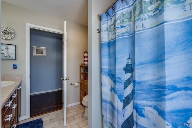 bathroom featuring toilet, vanity, and baseboards