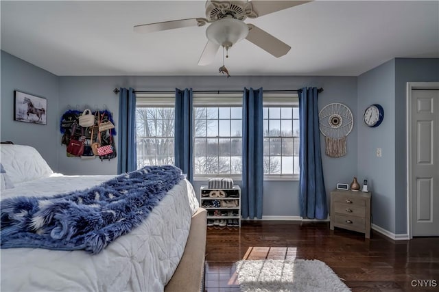 bedroom featuring dark wood-style flooring, multiple windows, a ceiling fan, and baseboards