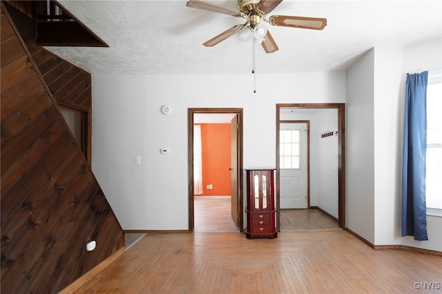 unfurnished room featuring a textured ceiling, wood finished floors, a ceiling fan, and baseboards