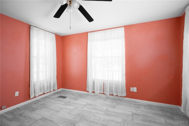 unfurnished room with visible vents, baseboards, and a ceiling fan