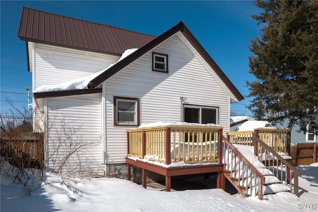 snow covered house with metal roof and a deck