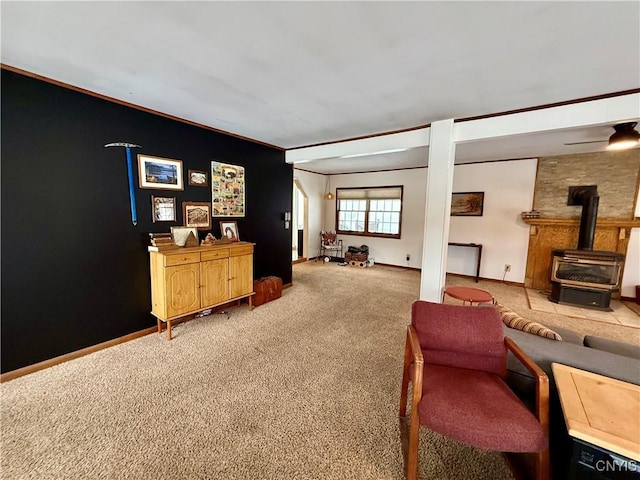 living area with a wood stove, crown molding, baseboards, and carpet flooring