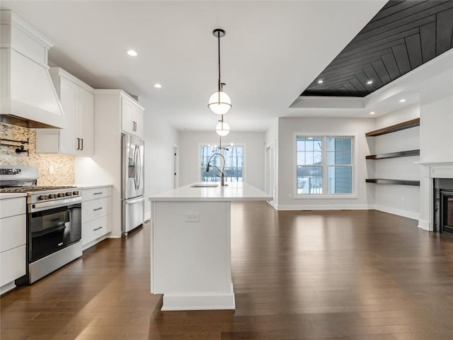 kitchen featuring a kitchen island with sink, a sink, white cabinets, light countertops, and appliances with stainless steel finishes