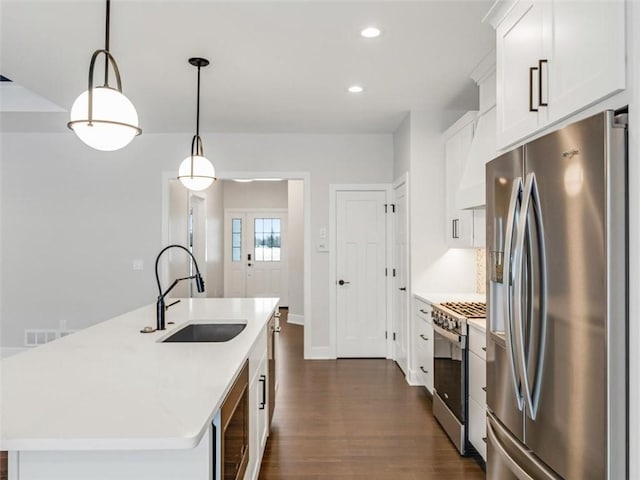 kitchen featuring decorative light fixtures, stainless steel appliances, a sink, light countertops, and a center island with sink