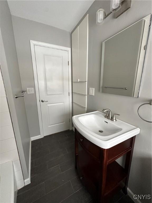 full bathroom featuring a bathtub, vanity, baseboards, and wood finished floors