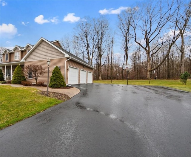 view of side of home with aphalt driveway, a lawn, and a garage