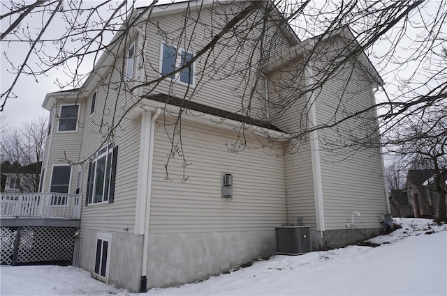 view of snowy exterior with central air condition unit and a wooden deck