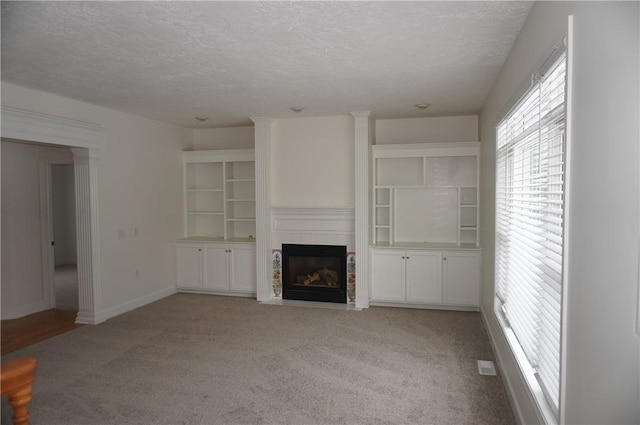 unfurnished living room with a fireplace with flush hearth, light colored carpet, a textured ceiling, and baseboards