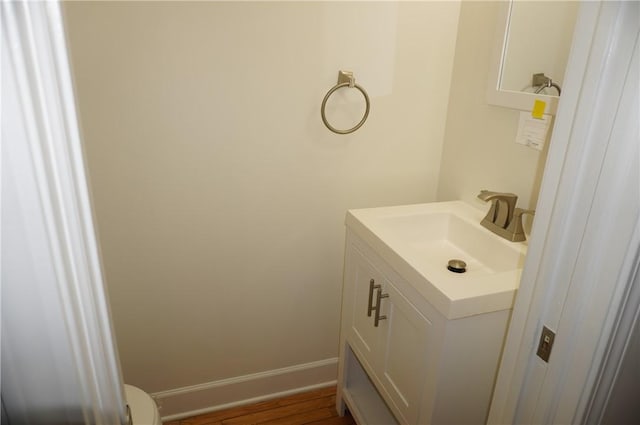 bathroom with toilet, vanity, and baseboards