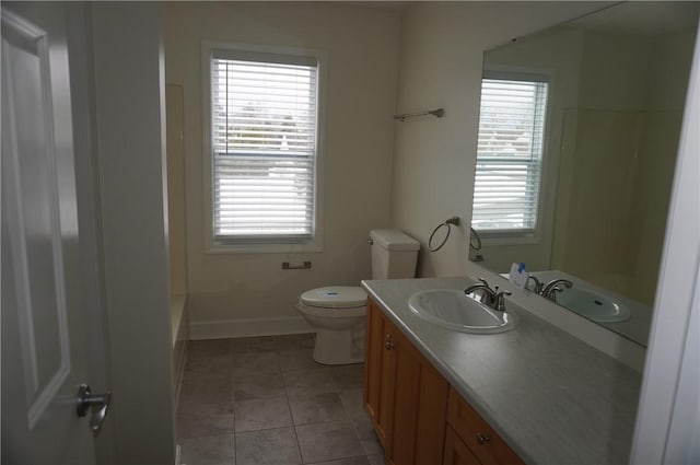 bathroom with toilet, tile patterned flooring, vanity, and a healthy amount of sunlight