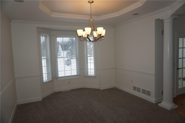 empty room featuring visible vents, dark colored carpet, a tray ceiling, decorative columns, and crown molding