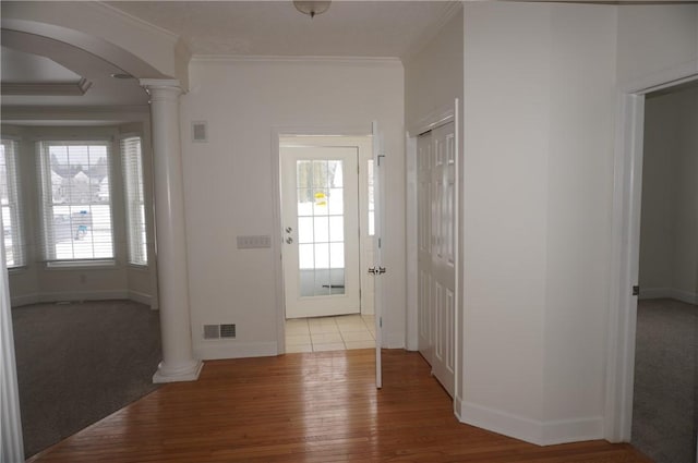 entryway featuring arched walkways, ornamental molding, decorative columns, and a healthy amount of sunlight