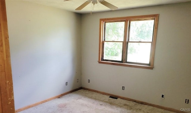 spare room featuring light carpet, ceiling fan, visible vents, and baseboards