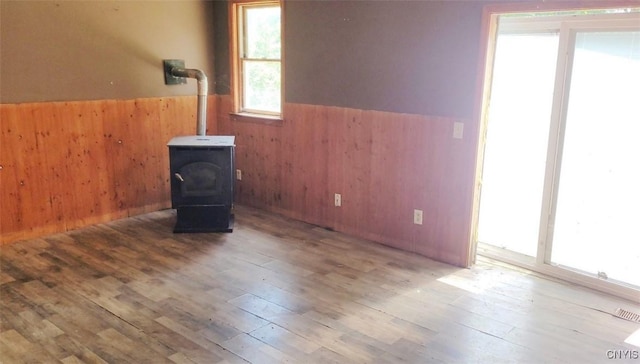 interior space featuring wainscoting, wood finished floors, a wood stove, and wooden walls