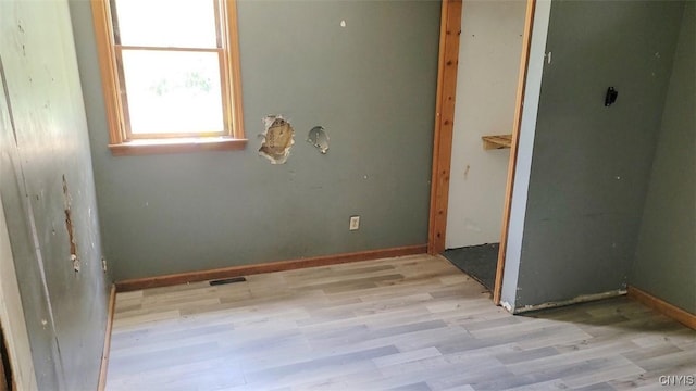 spare room featuring visible vents, light wood-style flooring, and baseboards