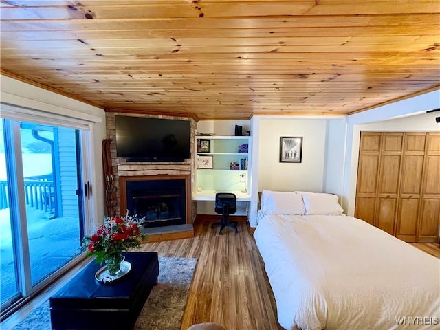 bedroom featuring a fireplace with raised hearth, light wood-type flooring, wood ceiling, and access to exterior