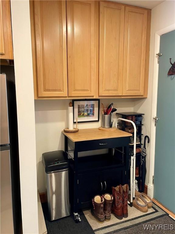 kitchen with light brown cabinetry, light countertops, and freestanding refrigerator