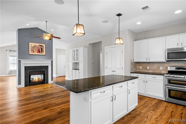 kitchen featuring stainless steel appliances, open floor plan, white cabinets, and a kitchen island