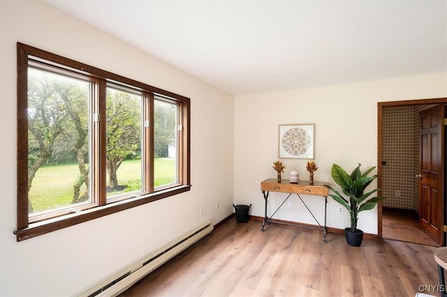 spare room featuring light wood finished floors, baseboard heating, and baseboards