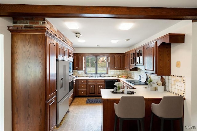 kitchen featuring glass insert cabinets, a breakfast bar area, a peninsula, light countertops, and black appliances