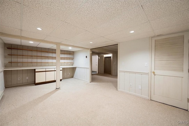 finished below grade area featuring recessed lighting, a wainscoted wall, light colored carpet, and a paneled ceiling