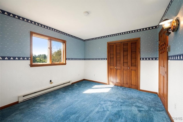 unfurnished bedroom featuring carpet, a closet, a baseboard heating unit, baseboards, and wallpapered walls