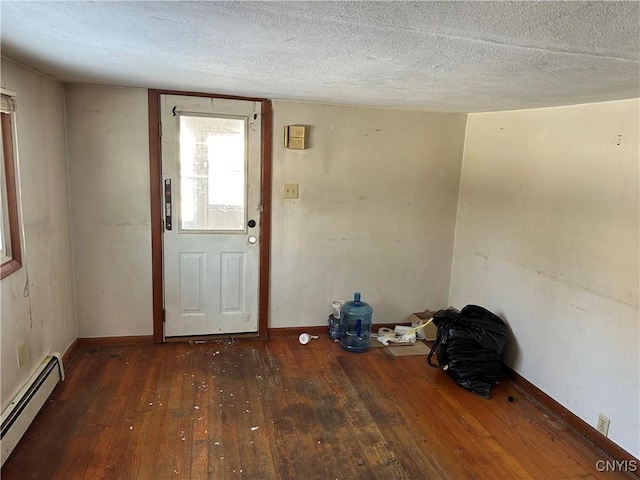 interior space featuring a baseboard heating unit, a textured ceiling, dark wood finished floors, and baseboards