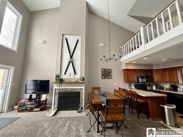 dining area featuring light colored carpet, a towering ceiling, a tiled fireplace, and an inviting chandelier