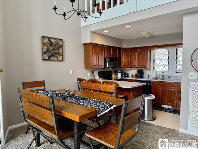 kitchen featuring light countertops, an inviting chandelier, a sink, black appliances, and baseboards