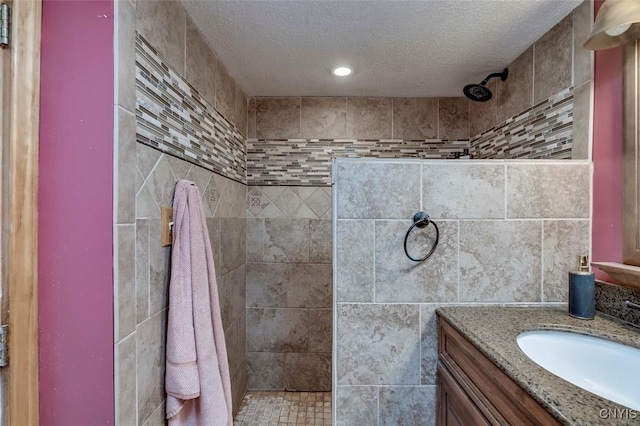 bathroom with a textured ceiling, walk in shower, vanity, and recessed lighting