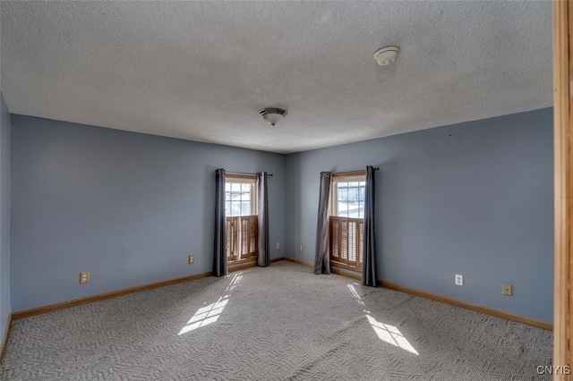 empty room with baseboards, a textured ceiling, and light colored carpet