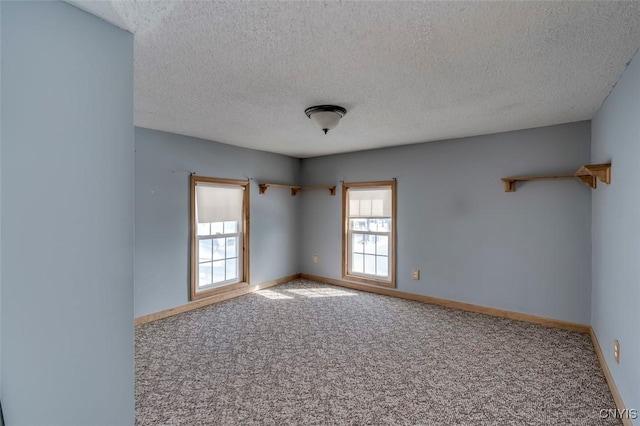 carpeted empty room featuring baseboards and a textured ceiling