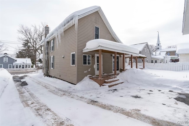 view of front of home with covered porch, fence, and a chimney